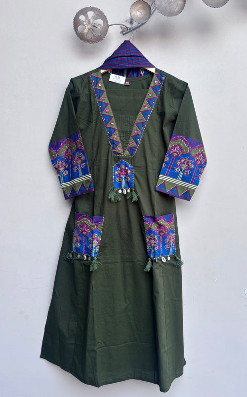 An olive green long-sleeve tunic or kaftan dress with colorful embroidered details on the neckline, cuffs, and pockets, hanging on a patterned hanger against a plain wall.