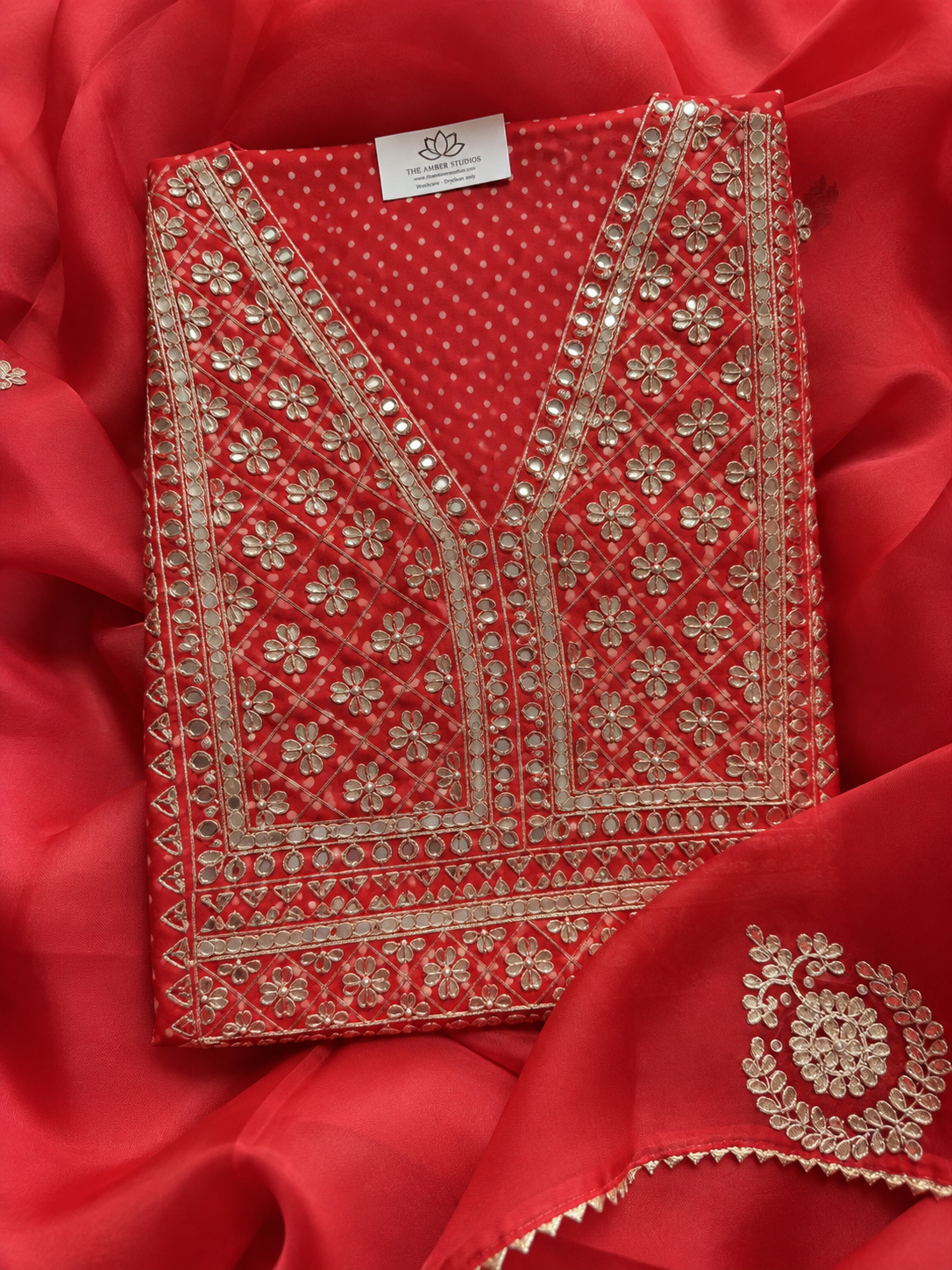 A red embroidered kurta top with intricate gold floral and geometric embroidery, laid flat on a matching red embroidered dupatta.